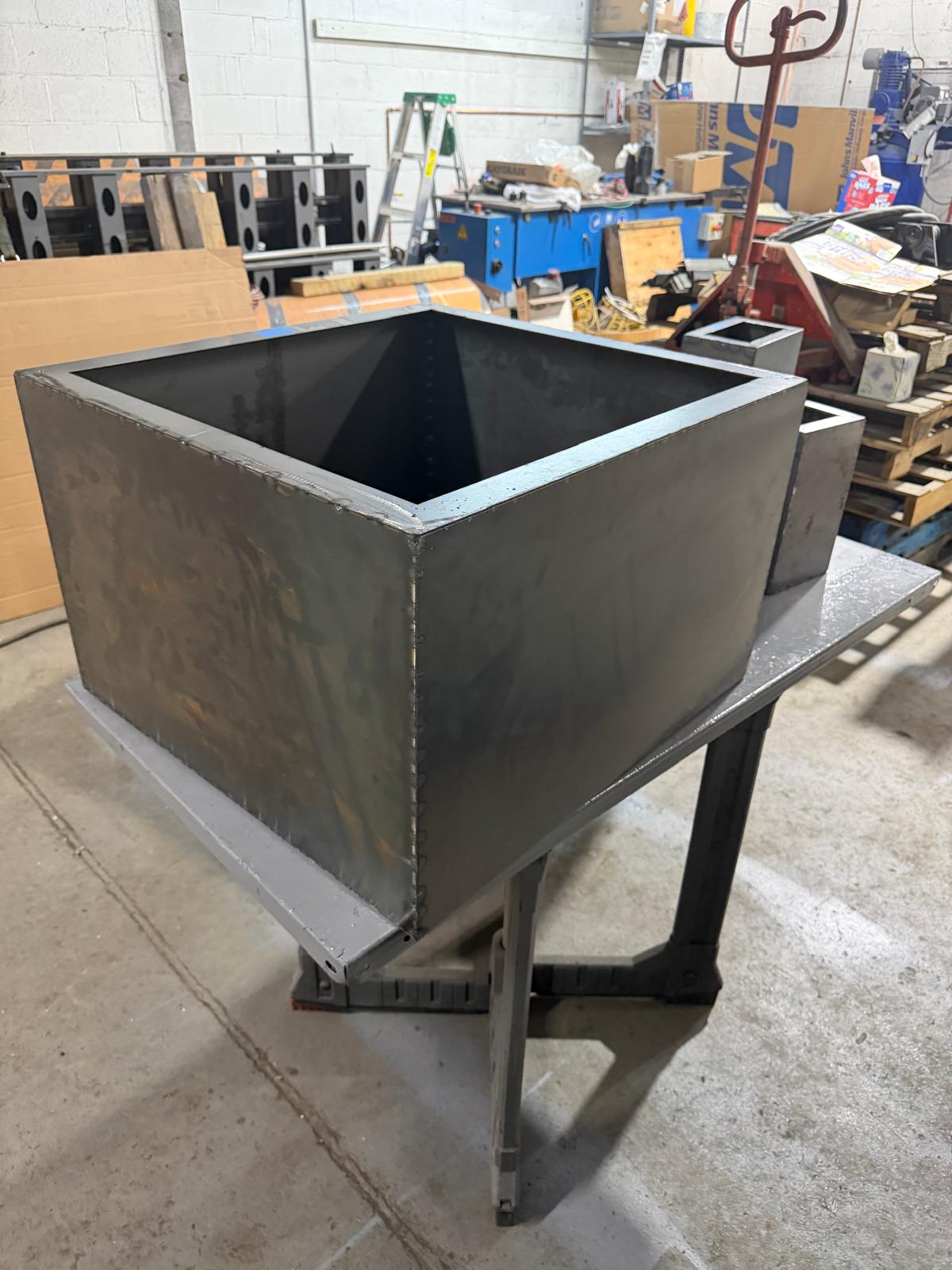 Open-top fabricated sheet metal curb on a work stand